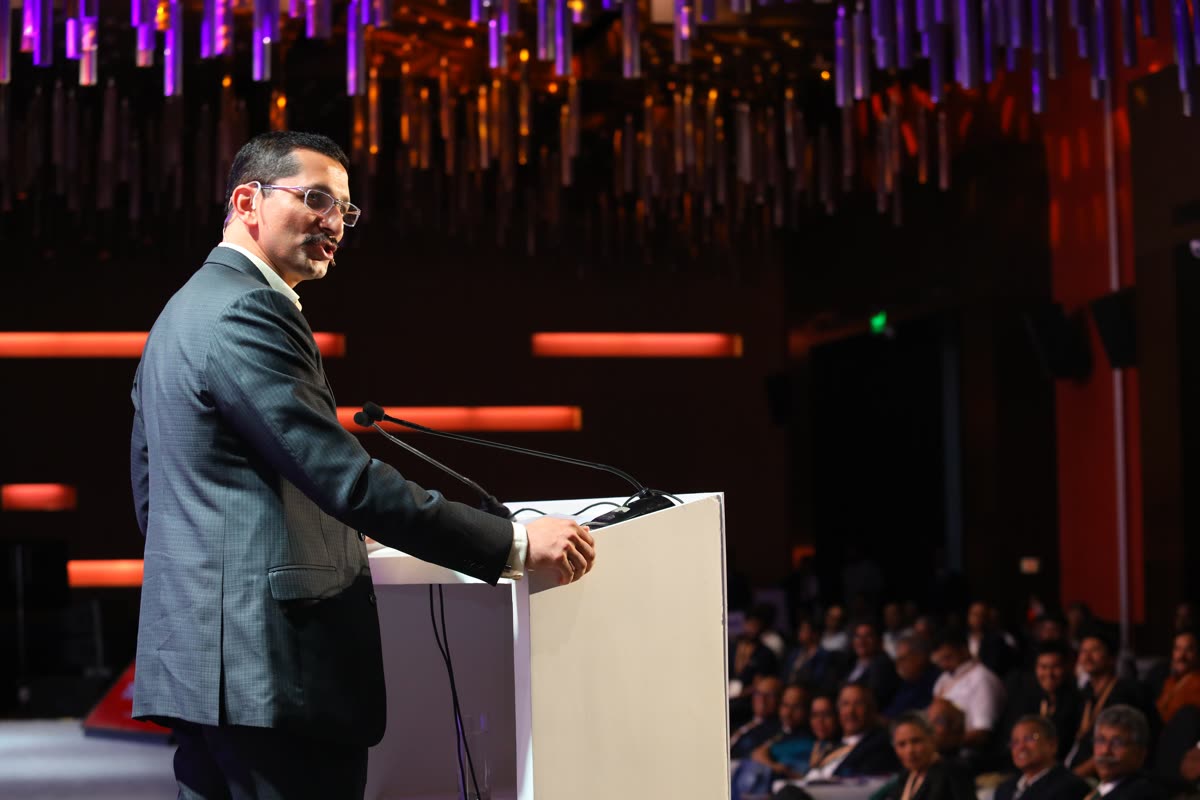 Chinmay addressing a large audience on a lit main stage